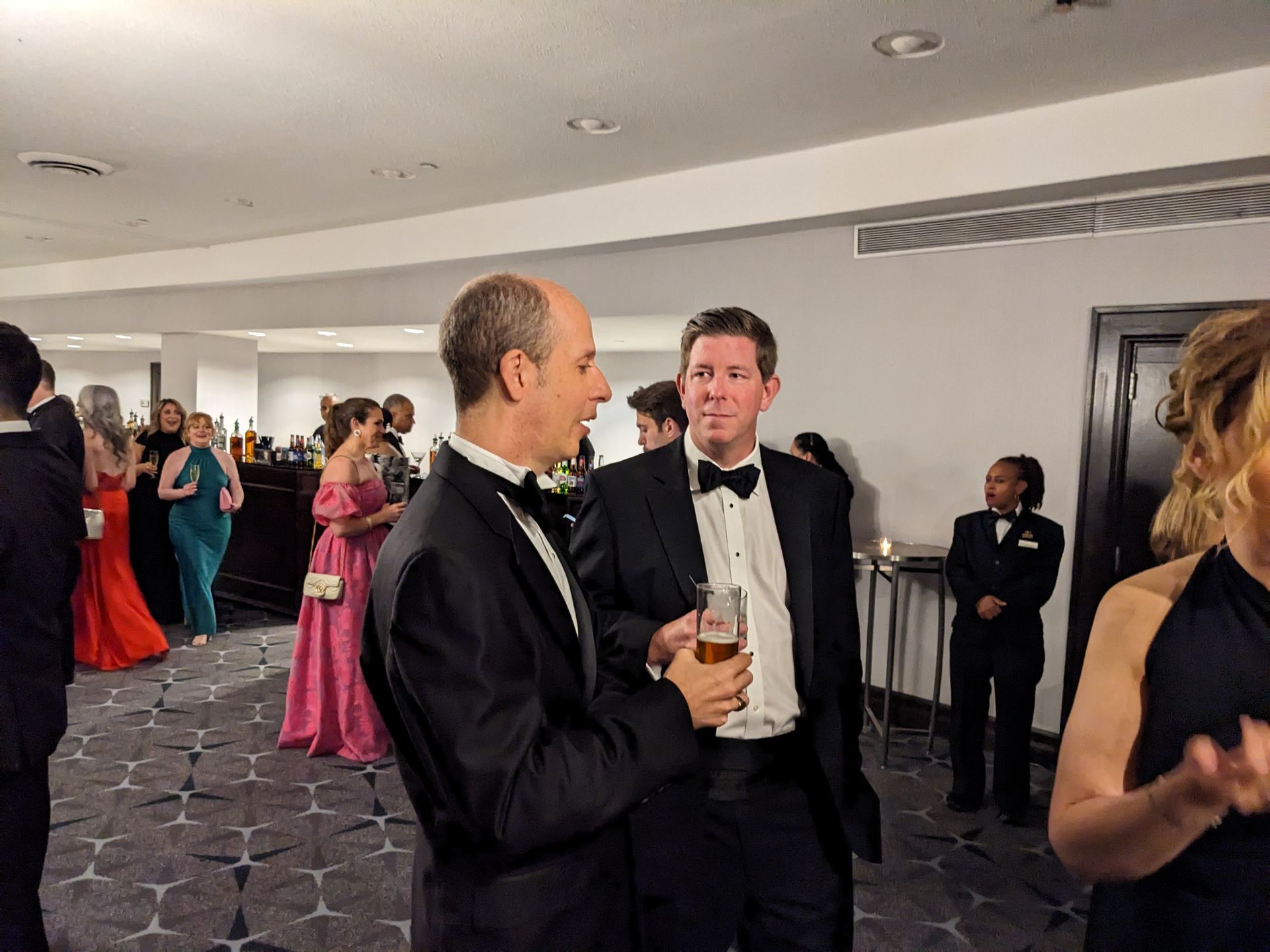 A group of people are standing in a room talking to each other.