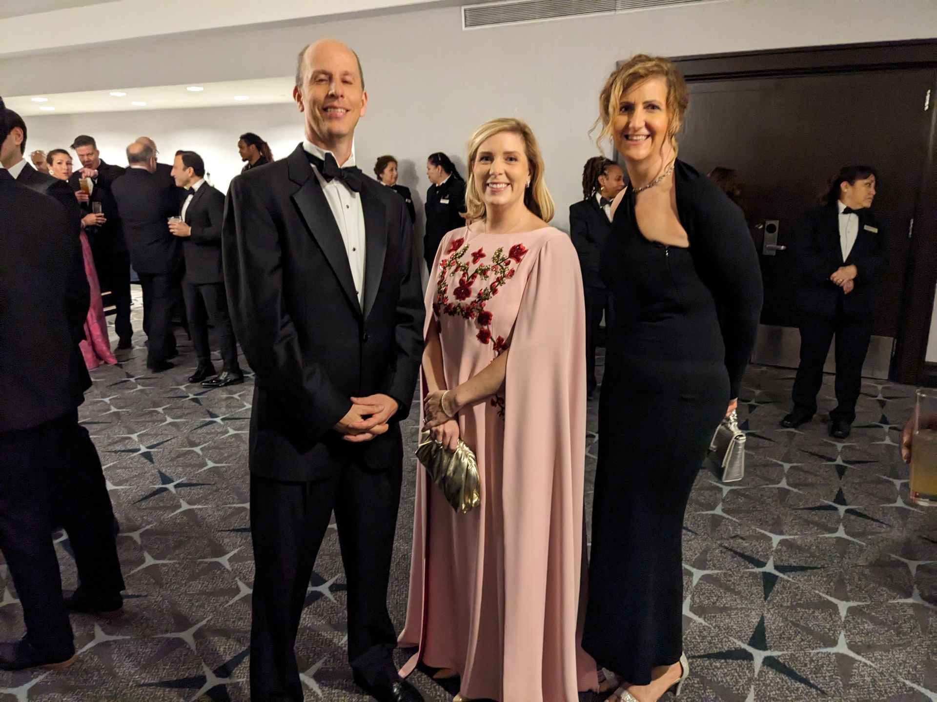 A man in a tuxedo and two women are posing for a picture