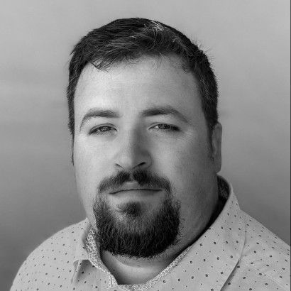 A black and white photo of a man with a beard wearing a white shirt.