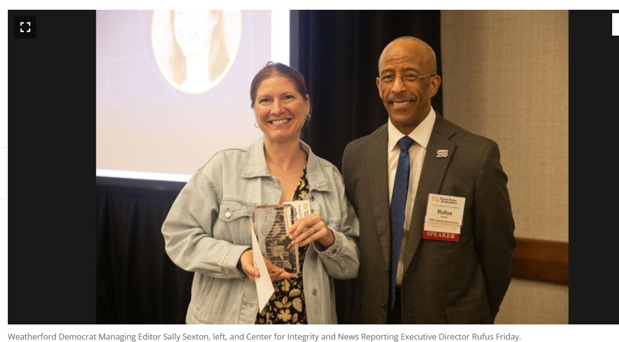 Two people smiling and holding an award plaque at a formal event