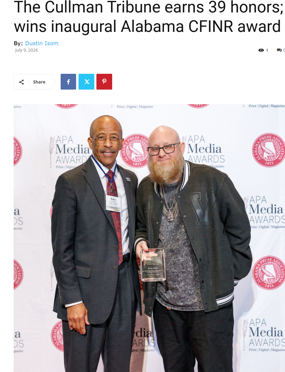 Two men holding an award at a media event, standing before a branded backdrop.