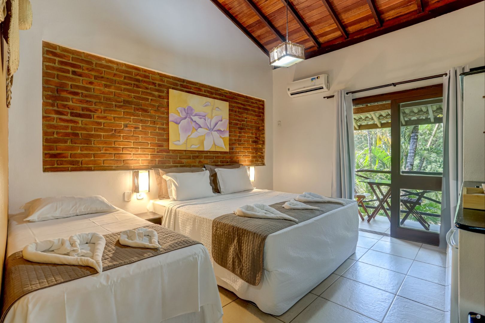 Um quarto de hotel com três camas e uma varanda.