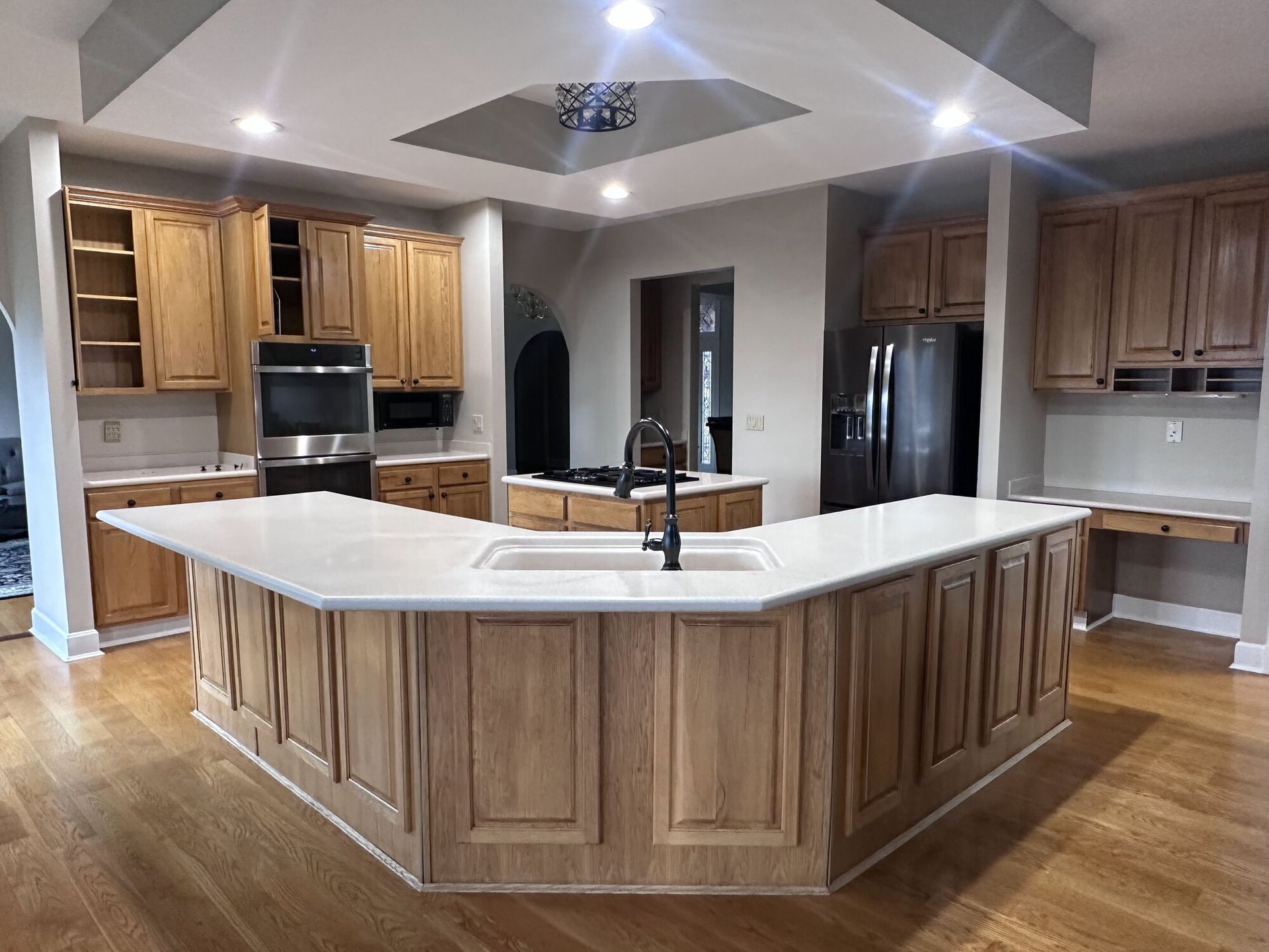 Large modern kitchen with a white island, wood cabinets, stainless appliances, and hardwood floors