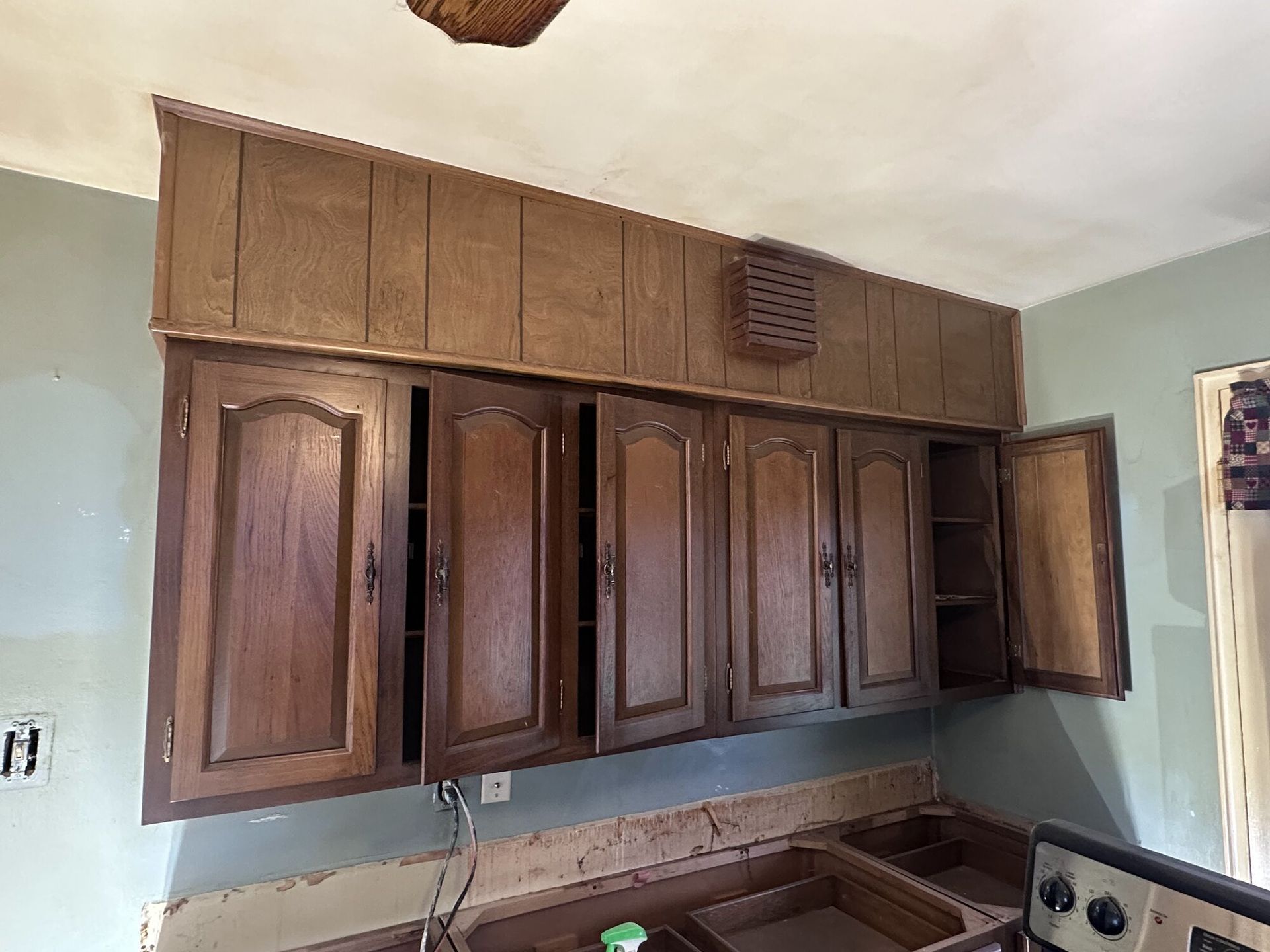 Wooden kitchen cabinets mounted above a countertop, with an open cabinet door on the right.