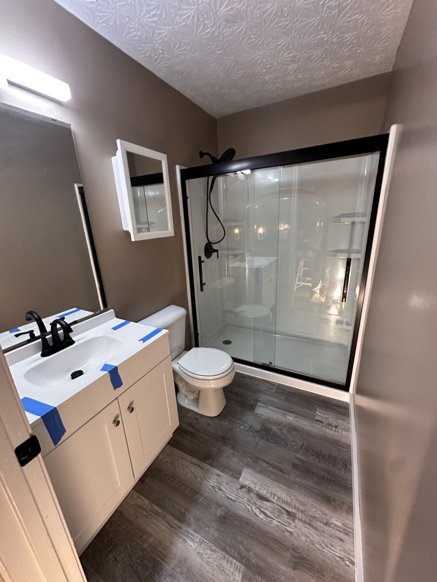 Small modern bathroom with vanity, toilet, and glass-enclosed shower in gray tones