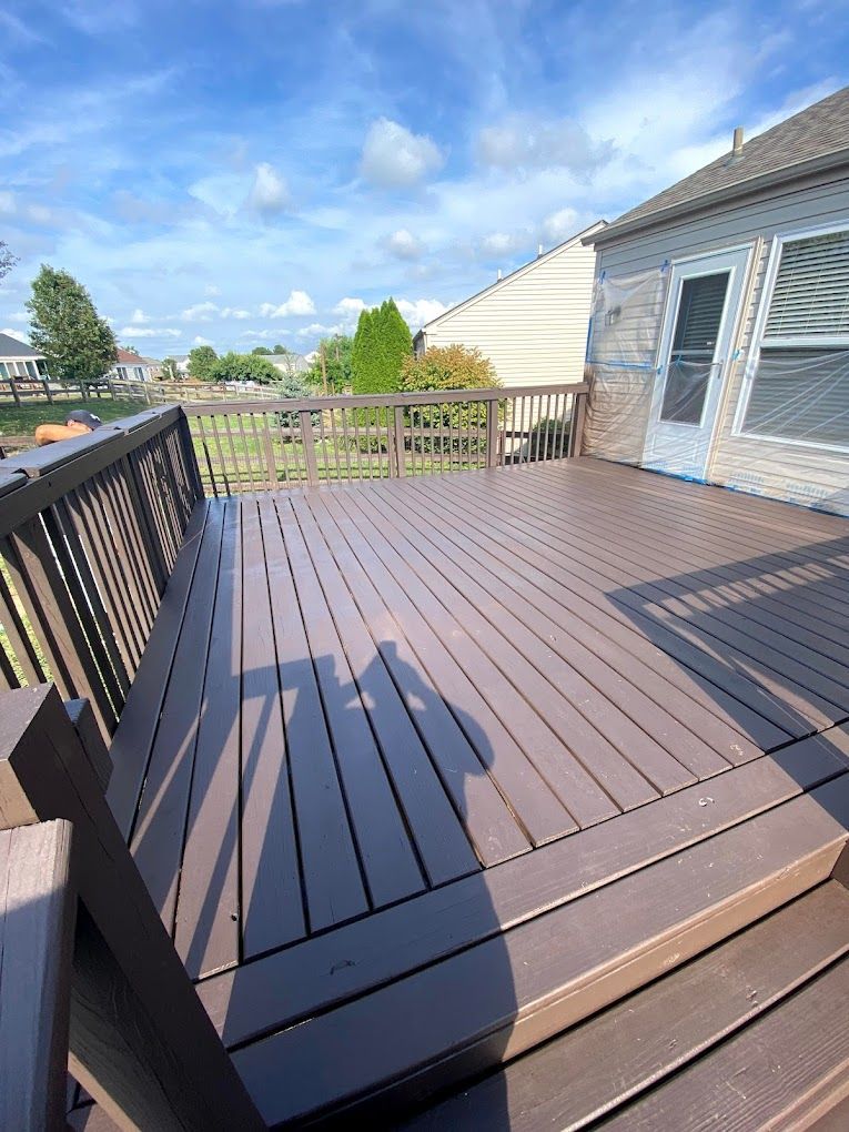 A wooden deck with a bench and a house in the background.