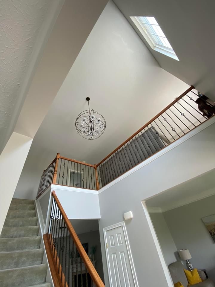 A staircase in a house with a skylight and a chandelier hanging from the ceiling.