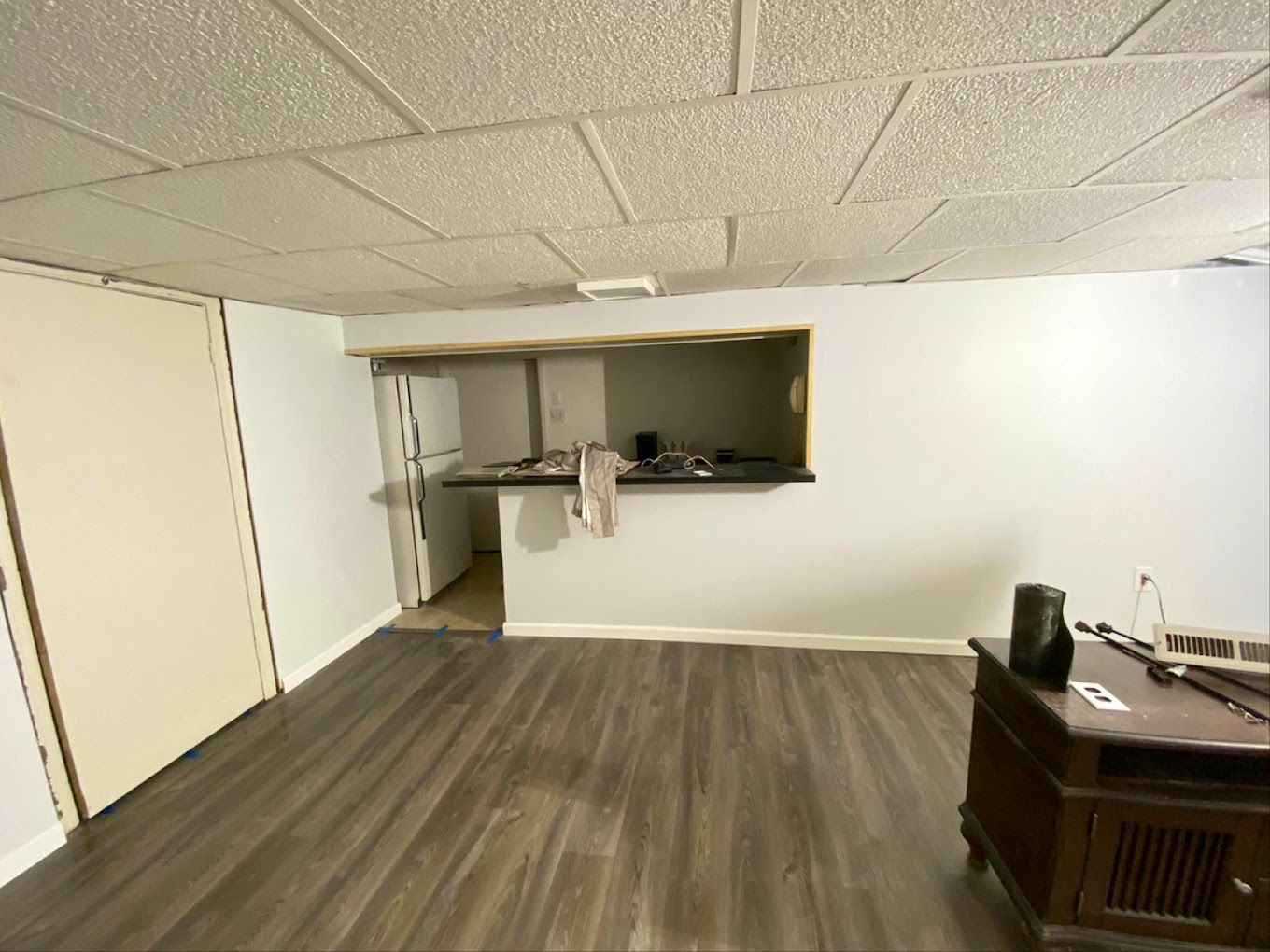 An empty living room with hardwood floors and a television.