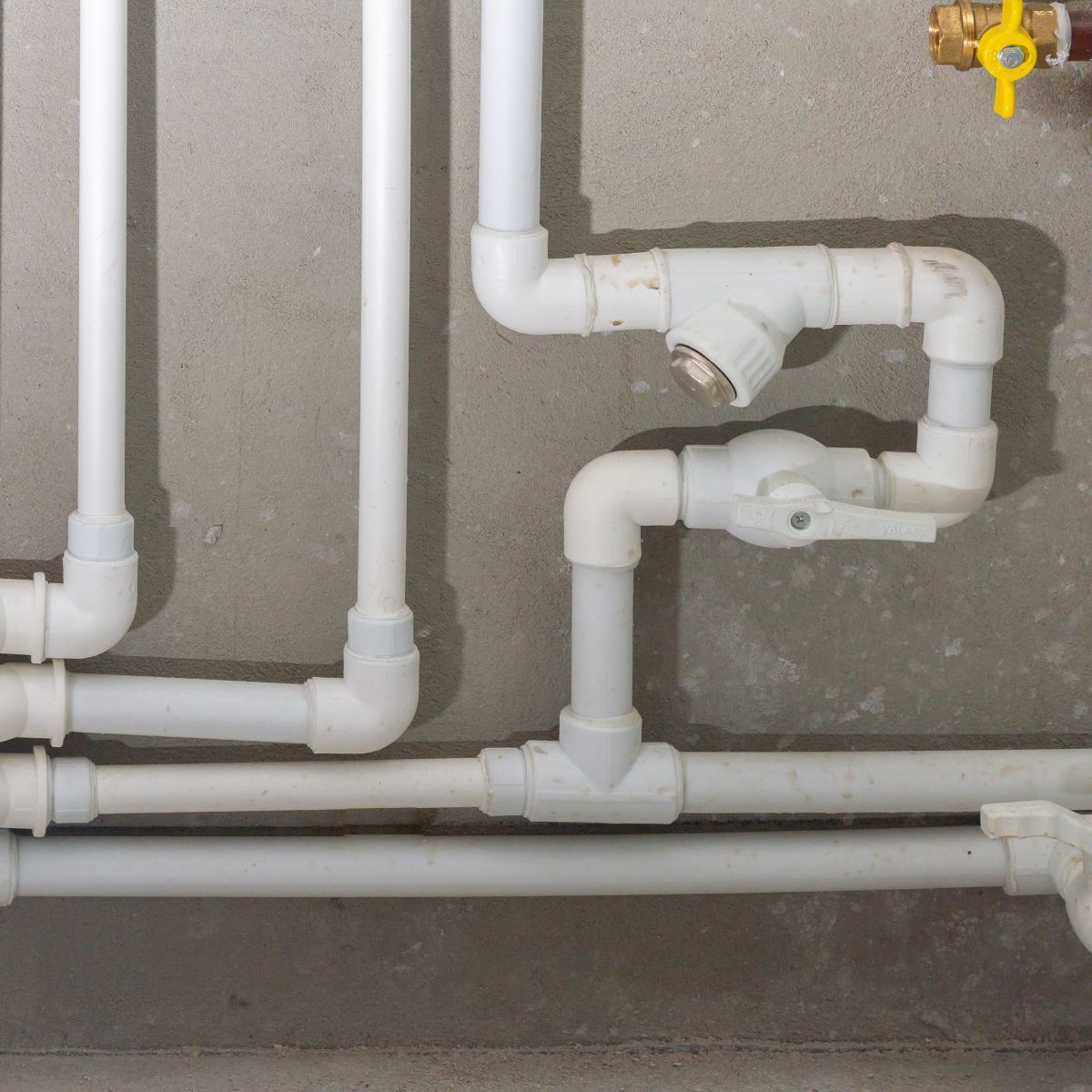 A bunch of white pipes with a yellow valve