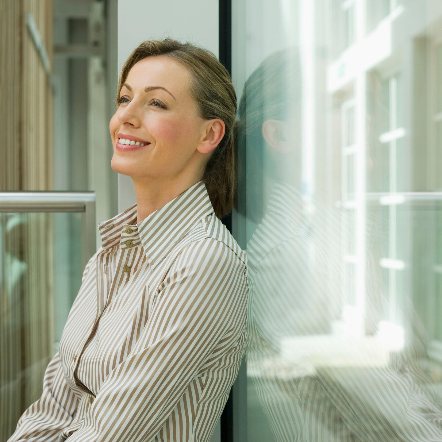 Woman smiling at a laptop on a wooden table in a bright room