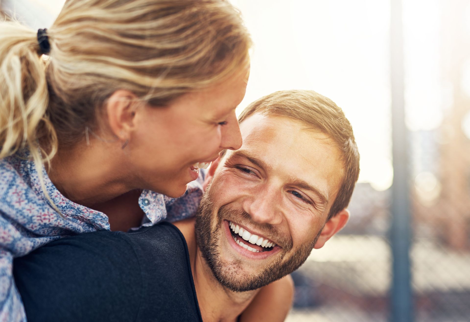 Smiling couple embracing outdoors in warm sunlight