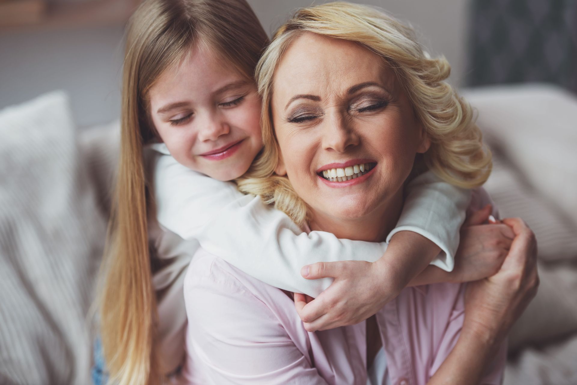 Woman smiling while hugging a child on a couch