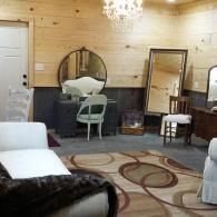 Vintage bedroom with vanity, mirror, white chairs, patterned rug, and soft beige walls