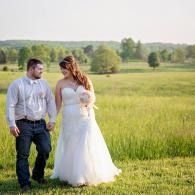 Couple walking hand in hand through a green field at sunset