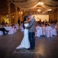 Bride and groom dancing at a warmly lit wedding reception under draped string lights