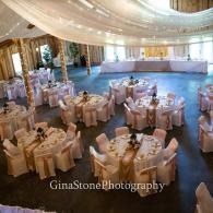 Elegant ballroom with round white-clothed tables set for a formal event under a domed ceiling.