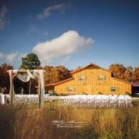 Yellow barn with white chairs outdoors under a blue sky, set in a grassy autumn field