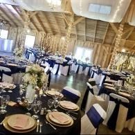 Banquet hall with round tables, white-and-navy chair covers, and floral centerpieces set for an event