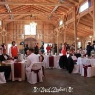Guests seated at round tables in a rustic wooden barn wedding reception hall