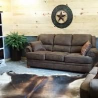 Brown sofa in a rustic living room with a star wall decoration, potted plant, and cowhide rug.