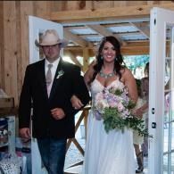 Bride and groom entering a rustic chapel, the bride holding a bouquet and smiling