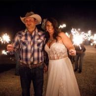 Couple in western attire holding sparklers at a nighttime outdoor celebration
