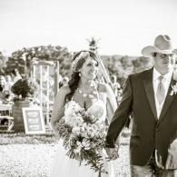 Bride and groom walking outdoors, bride holding a bouquet and groom wearing a cowboy hat