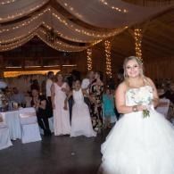 Woman in a white gown holding a bouquet at a decorated wedding reception.