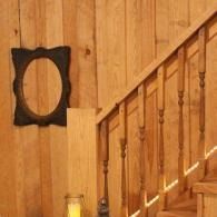 Wood-paneled stairwell with a wooden banister and a small oval mirror on the wall