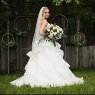 Bride in white gown holding bouquet in a garden setting