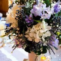 White and lavender floral bouquet with candles on a table