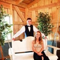 Couple posing on a white bench in a rustic wooden room with potted plants and soft natural light