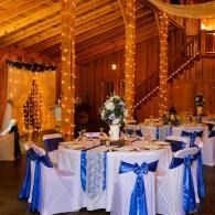 Elegant banquet table with blue-and-white decor in a warmly lit wooden hall with string lights