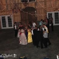 People dancing in formal attire at an outdoor evening celebration under string lights.