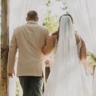 Bride and groom walking away together under a white canopy at an outdoor wedding