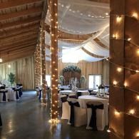 Elegant tented banquet hall with twinkling string lights, draped fabric, and round tables set for an event