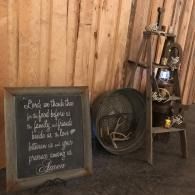 Rustic decor with a chalkboard sign, large spool, and shelving against a wooden wall
