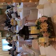 Elegant banquet table set with pink floral centerpiece, white linens, and folded napkins in a decorated hall