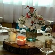 Decorated table centerpiece with flowers, candles, and glassware on a white tablecloth