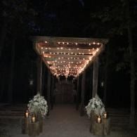 String-lit walkway lined with white floral arrangements at night