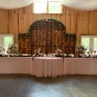 Decorated banquet table with white tablecloths and flower arrangements in a wood-paneled hall