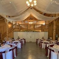 Elegant banquet hall with draped ceiling, wooden decor, and round tables set for an event