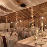 Decorated banquet hall with draped fabric, string lights, and white-clothed dining tables