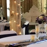 Decorated banquet table with candles, flowers, and draped lights in an elegant hall