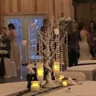 Decorated banquet table with lit candles and floral centerpiece in a warmly lit event hall