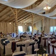 Elegant banquet hall with round tables, chairs, and white draped ceiling decorations