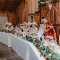 People seated at a long white-decorated banquet table in a rustic barn venue