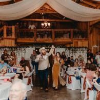 Couple dancing at a rustic wedding reception with guests seated at decorated tables