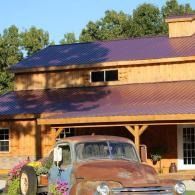 Rustic wooden house with purple metal roof and an old pickup truck parked out front