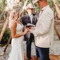 Outdoor wedding ceremony with bride and groom exchanging rings under trees